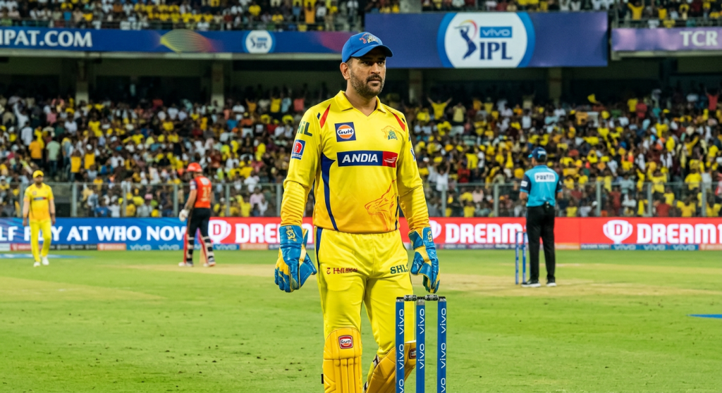 Wicketkeeper in yellow uniform standing behind stumps on cricket field